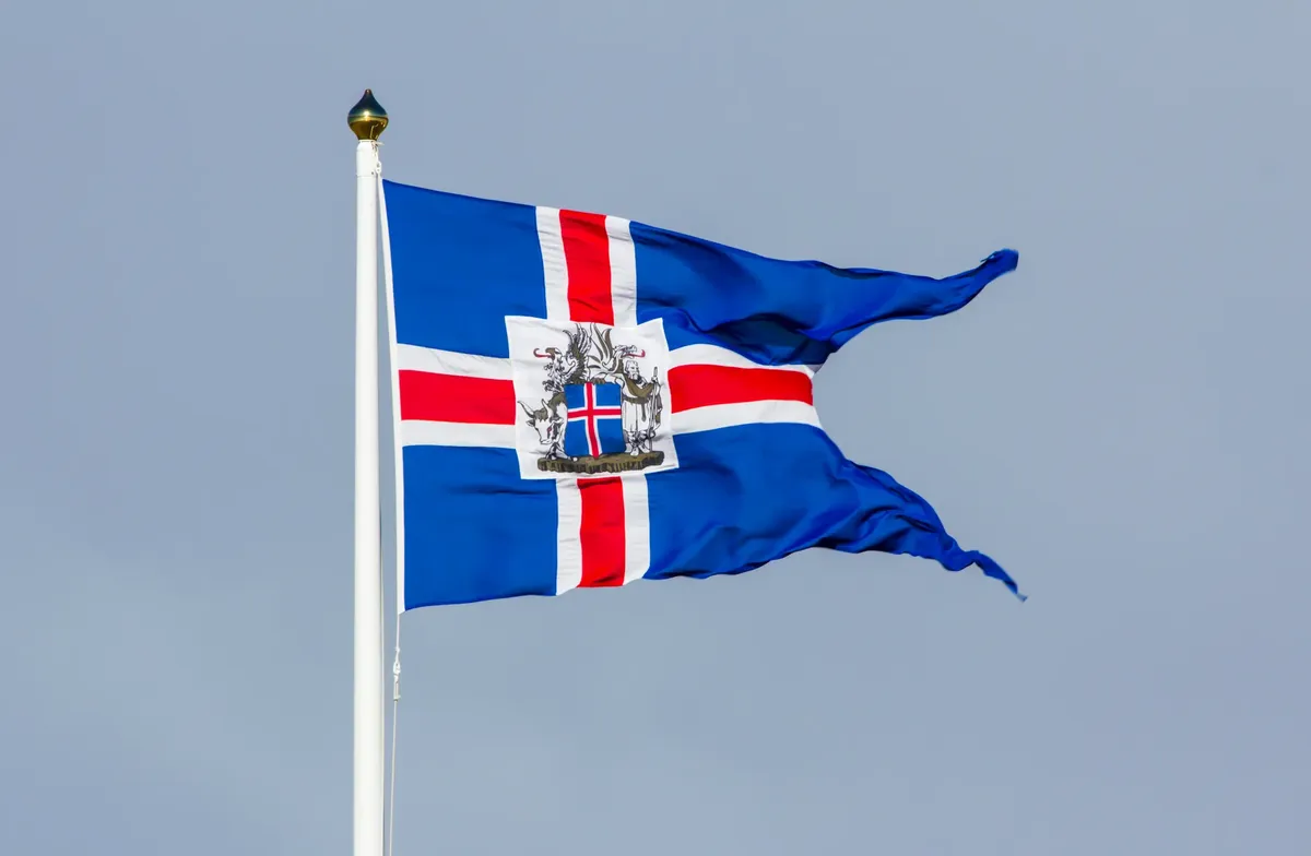 Close-up of Iceland regional flag waving against a clear sky in Alftanes.